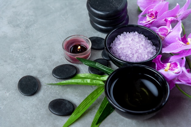 Foto aceite de aromaterapia de naturaleza orquídea púrpura flor spa con velas y spa de piedra.