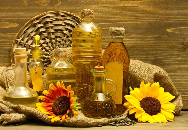 Aceite en botellas de girasoles y semillas sobre fondo de madera