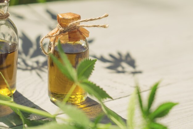 Aceite de cáñamo en botellas pequeñas sobre una superficie de madera blanca