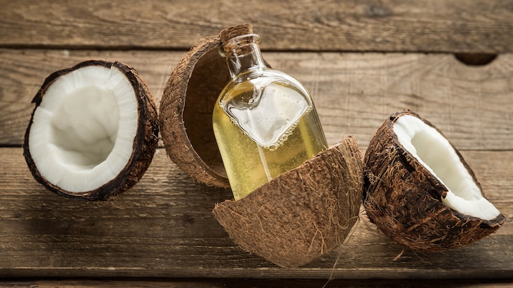 Aceite de coco en una botella y coco sobre un fondo de madera Productos para el cuidado del cabello