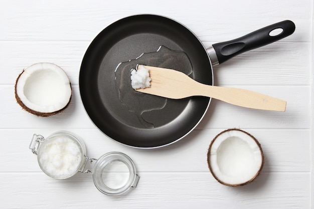 El aceite de coco y una sartén sobre una mesa de madera closeup