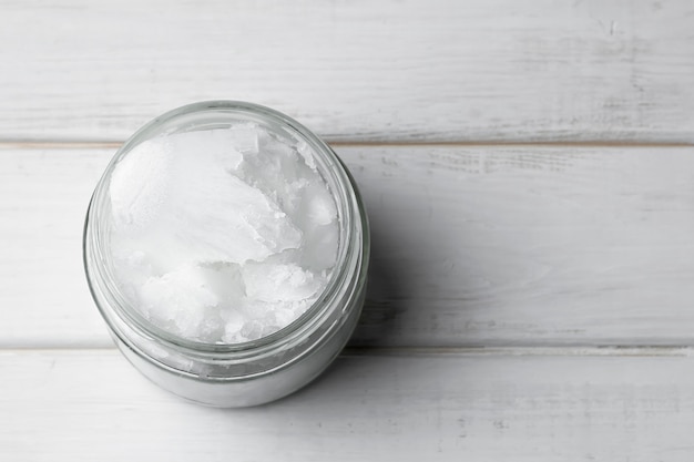 Foto aceite de coco en un tarro de cristal en un fondo blanco.