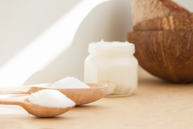 Aceite de coco en tarro y cuchara de madera. Cuerpo de la naturaleza, cara, concepto de cuidado del cabello.