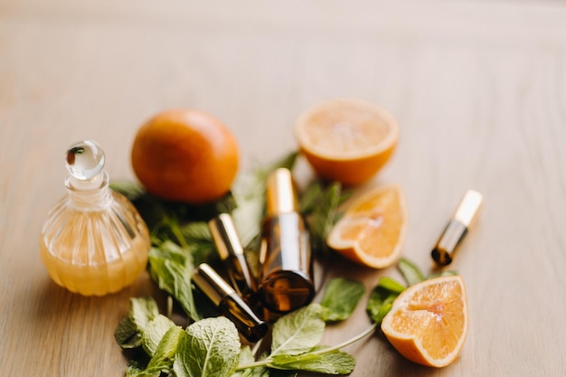 Foto aceite esencial en botellas con aroma de naranja y menta sobre una superficie de madera