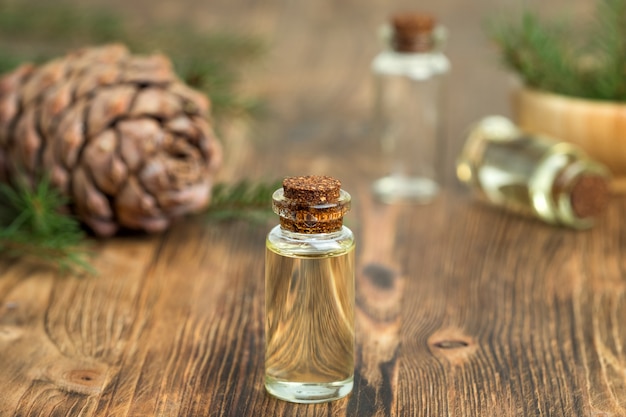 Aceite esencial de cedro en una botella de vidrio. Enfoque suave. Fondo de madera