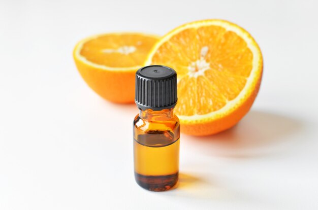 Aceite esencial de cítricos de naranja en botella de vidrio oscuro con frutas frescas de naranja