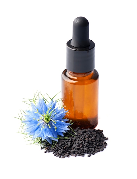 Aceite esencial de comino negro con flores de nigella sativa sobre fondos blancos.