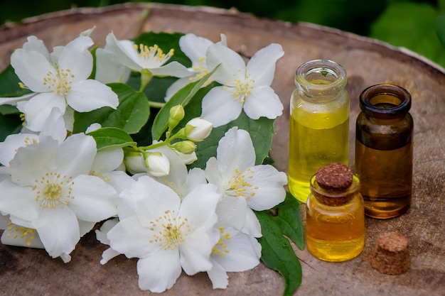 Aceite esencial y flores de jazmín sobre un fondo de madera. Procedimientos cosméticos. Enfoque selectivo