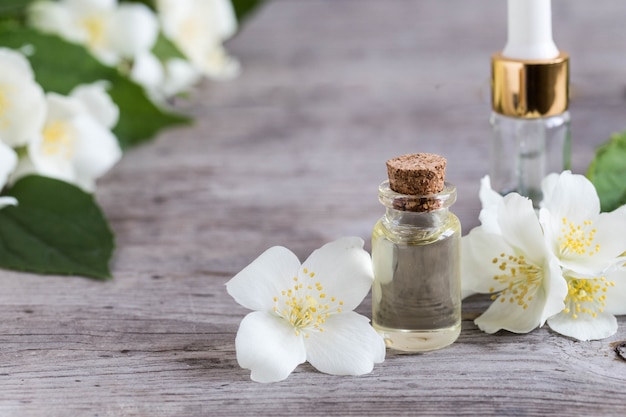 Aceite esencial de jazmín. Aceite de masaje con flores de jazmín sobre un fondo de madera