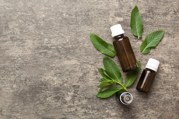 Aceite esencial de menta natural en una botella de vidrio cosmética orgánica con extractos de hierbas de menta sobre fondo de color