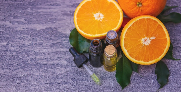 Aceite esencial de naranja en una botella, trozos de fruta fresca en la superficie