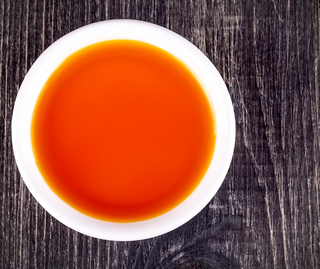 El aceite de espino amarillo en la pequeña taza blanca de madera vieja