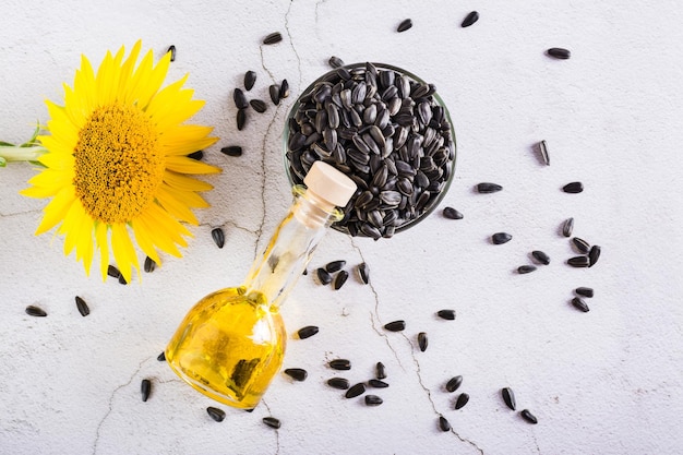 Aceite de girasol en una botella y semillas en un recipiente sobre la mesa Cosecha y nutrición natural Vista superior