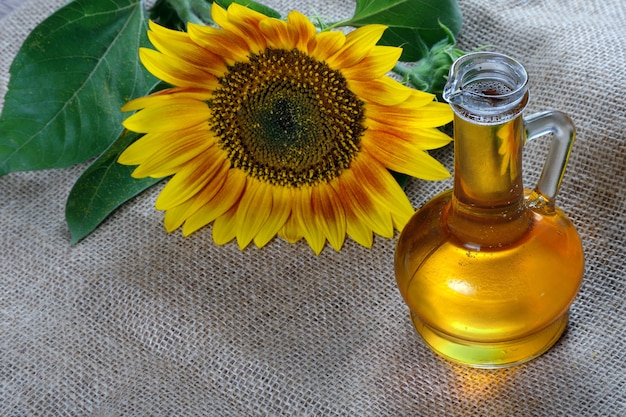 Aceite de girasol y una flor de girasol sobre la mesa. aceite vegetal natural.