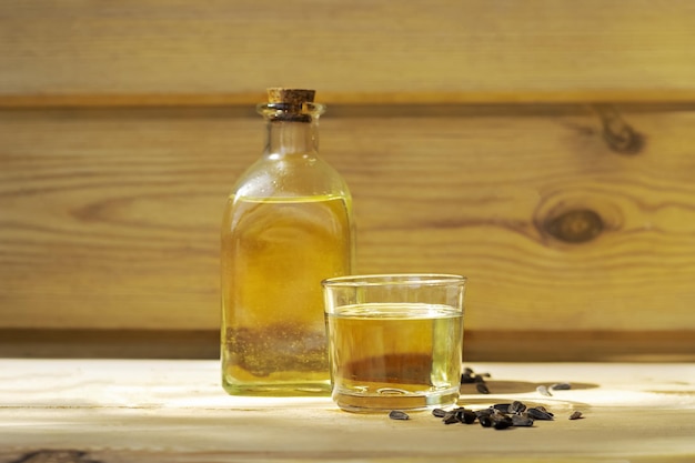 Aceite de girasol en un vaso de botella con semillas sobre fondo de madera