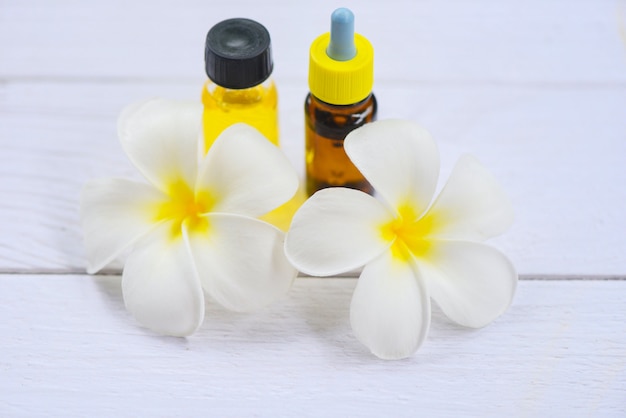 Aceite de hierbas aromáticas aromaterapia botellas con flor blanca Frangipani Plumeriaon - Aceites esenciales naturales en mesa de madera y minimalista orgánico