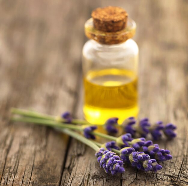 Aceite de lavanda con flor sobre superficie de madera