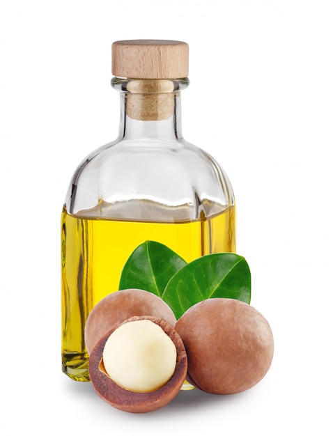 Aceite de macadamia en botella cuadrada y nueces con hojas