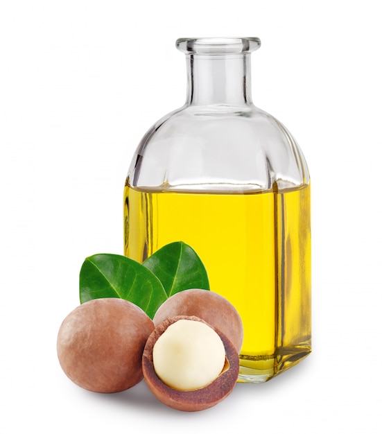 Aceite de macadamia en frasco de vidrio y nueces con hojas