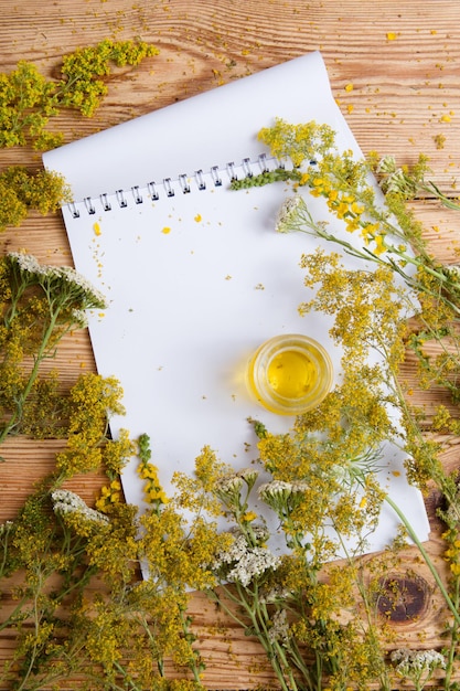 Aceite de masaje en una botella de vidrio y un bloc de notas sobre una mesa de madera