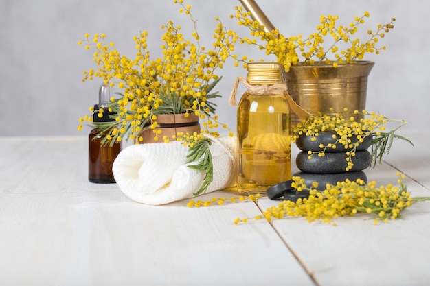 Aceite de masaje de flores de mimosa en botella de vidrio. De cerca