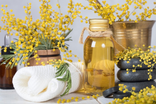 Aceite de masaje de flores de mimosa en botella de vidrio. De cerca