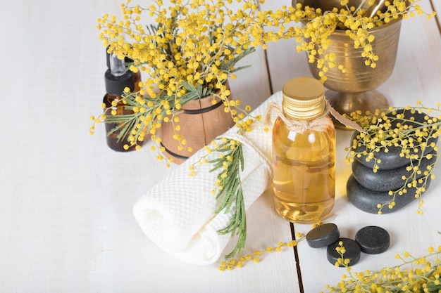 Aceite de masaje de flores de mimosa en botella de vidrio. De cerca