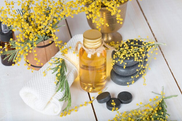 Aceite de masaje de flores de mimosa en botella de vidrio. De cerca