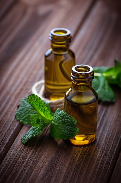 Aceite de menta en botellas pequeñas y menta fresca.