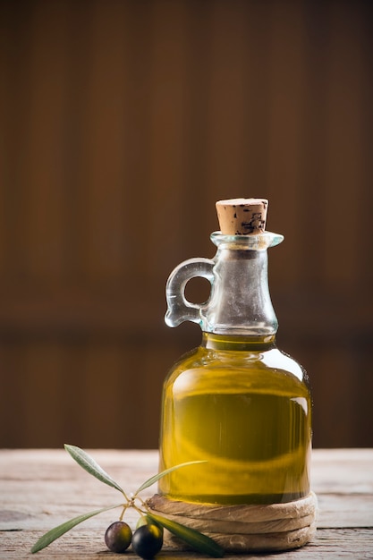 Foto aceite de oliva y aceitunas en mesa rústica de madera