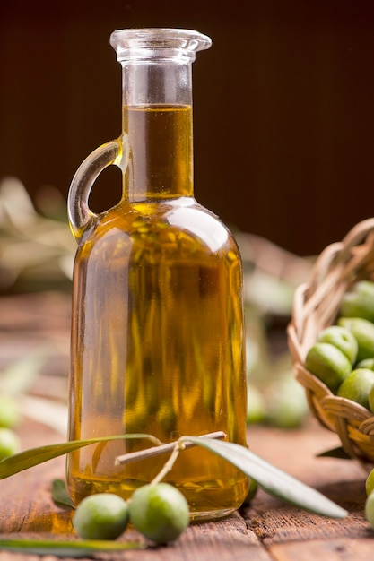 Foto aceite de oliva y aceitunas en mesa rústica de madera