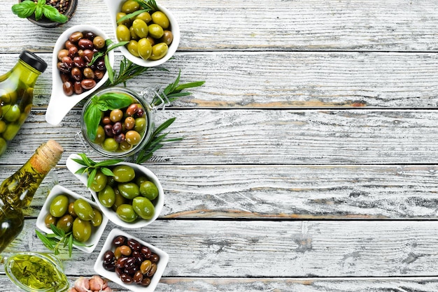 Aceite de oliva y aceitunas sobre un fondo blanco de madera Vista superior Espacio libre para el texto