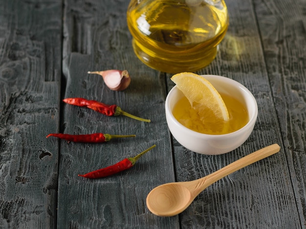 Aceite de oliva con ajo y limón y ají en un tazón blanco sobre una mesa de color negro oscuro. Aderezo para ensalada de dieta.