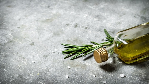 Aceite de oliva en botella con romero y sal sobre un fondo de piedra