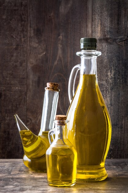 Foto aceite de oliva en diferentes botellas de vidrio en mesa de madera