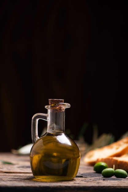 Aceite de oliva con pan sobre una mesa de madera. Composición rústica vintage