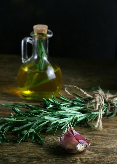 Aceite de oliva con romero sobre una mesa de madera Junto a él está el enfoque selectivo de romero oscuro y malhumorado