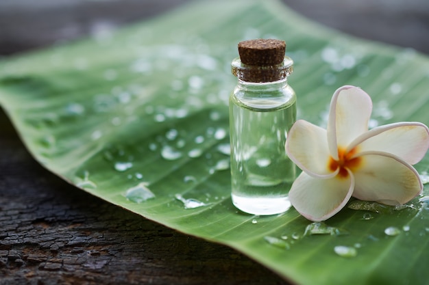 Aceite de plumeria en botella de vidrio con flor de plumeria en hoja de plátano