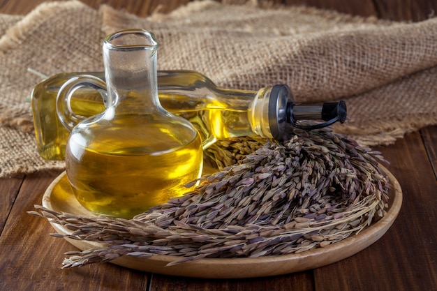 Aceite de salvado de arroz en botella de vidrio con semilla en madera