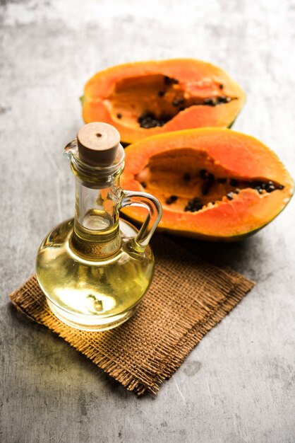 Aceite de semilla de papaya con papita cruda sobre una superficie cambiante. enfoque selectivo