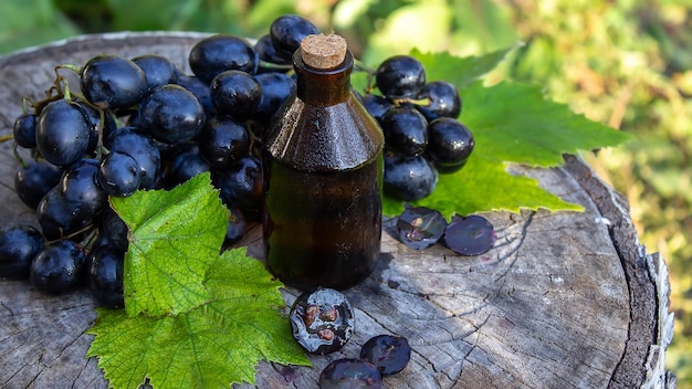 Aceite de semilla de uva en un frasco de vidrio y uvas frescas para spa y cuidado corporal El concepto de spa bio eco productos enfoque selectivo