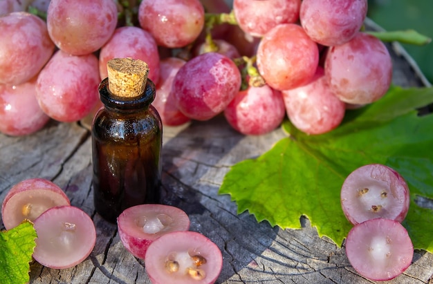 Aceite de semilla de uva en un frasco de vidrio y uvas frescas para spa y cuidado corporal El concepto de spa bio ecoproductos