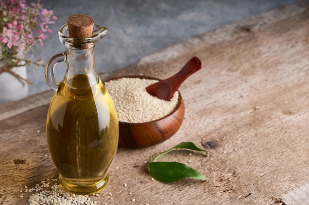 Aceite de sésamo en frasco de vidrio y semillas de sésamo en mesa de madera Copia espacio Rústico