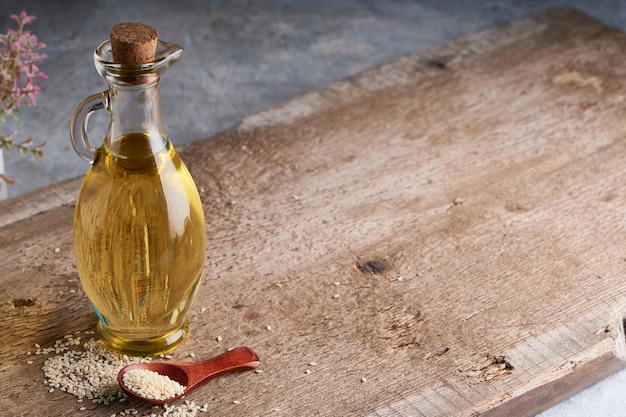 Aceite de sésamo en frasco de vidrio y semillas de sésamo en mesa de madera Copia espacio Rústico