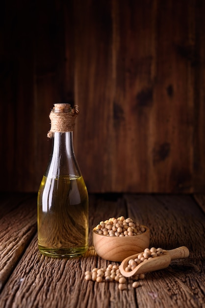 Aceite de soja con habas de soja sobre fondo de madera.