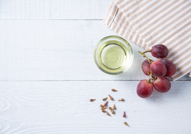 Aceite vegetal natural de semillas de uva en una botella transparente sobre el fondo de madera. Alimentos dietéticos saludables. Vista superior y espacio de copia.