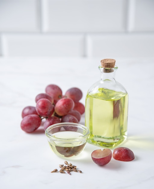 Aceite vegetal natural de semillas de uva en una botella transparente sobre la mesa de la cocina. Alimentos dietéticos saludables. Vista frontal