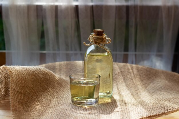 Aceite vegetal en un vaso de botella sobre fondo de tela de lona de arpillera