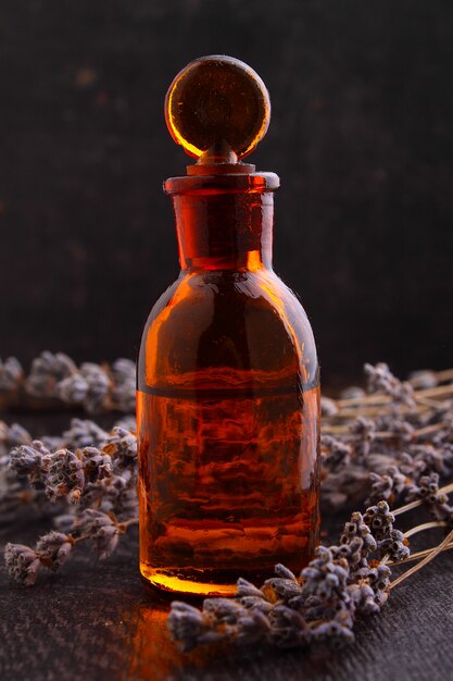 Foto aceites aromáticos con una rama de lavanda sobre un fondo oscuro.