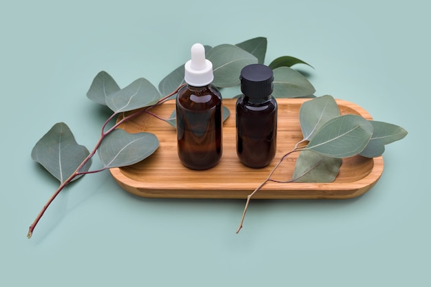 Aceites esenciales con hojas de eucalipto natural sobre fondo pastel de menta, productos de belleza, cuidado de la piel facial, concepto de tratamiento de belleza spa